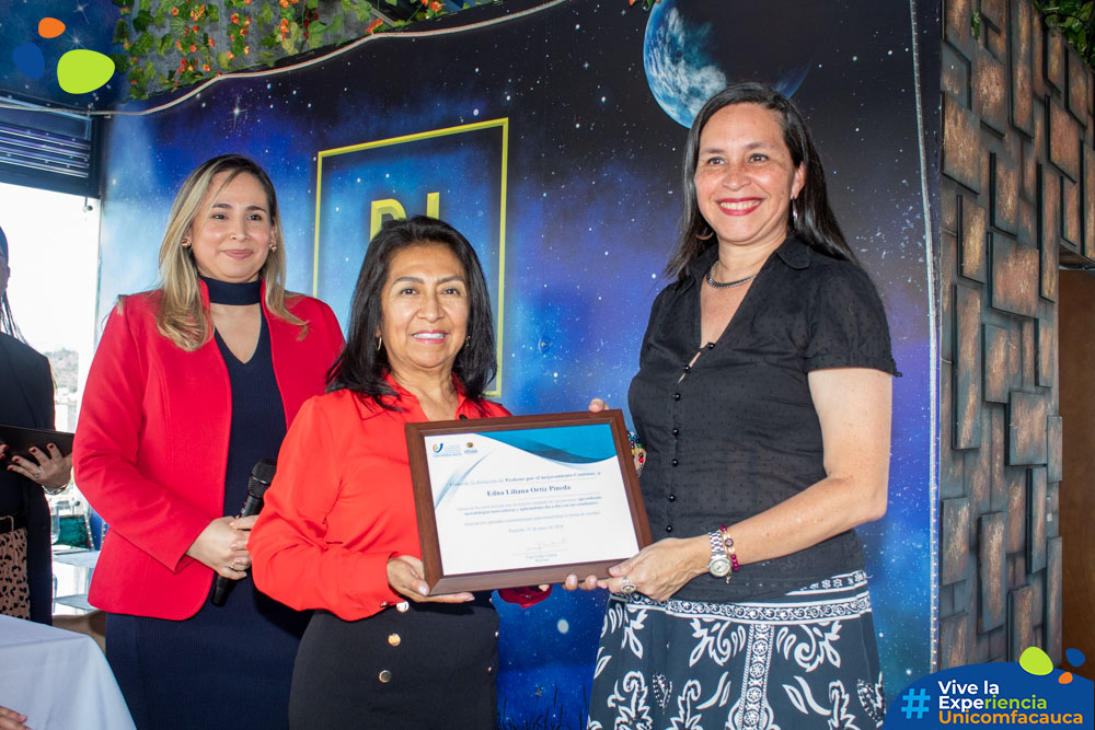 La Dra. Marisol Velasco, Jefe de Departamento de Desarrollo Institucional, en representación de la Caja de Compensación Familiar del Cauca - Comfacauca, entregando el reconocimiento a Edna Liliana Ortiz Pineda como profesora en mejoramiento continuo.