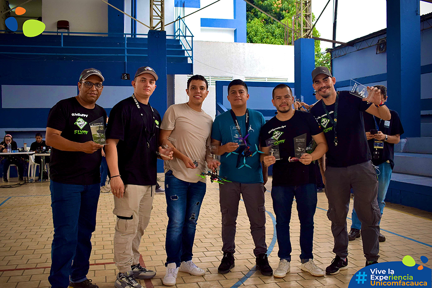 Miembros del Club, Santiago Ocampo y Andrés Quiñonez en el 5" Drone Racing junto con otros competidores de distintas universidades, cada uno con respectivo premio.