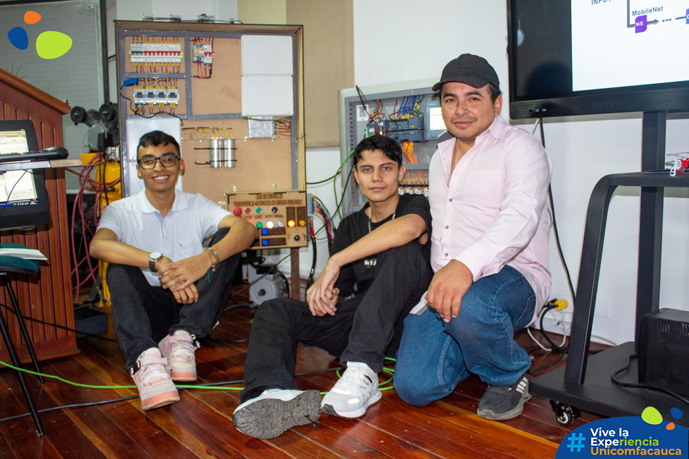 Tres chicos estudiante de Ingeniería Mecatrónica posando al lado de su proyecto en el Showroom Mechatronics.