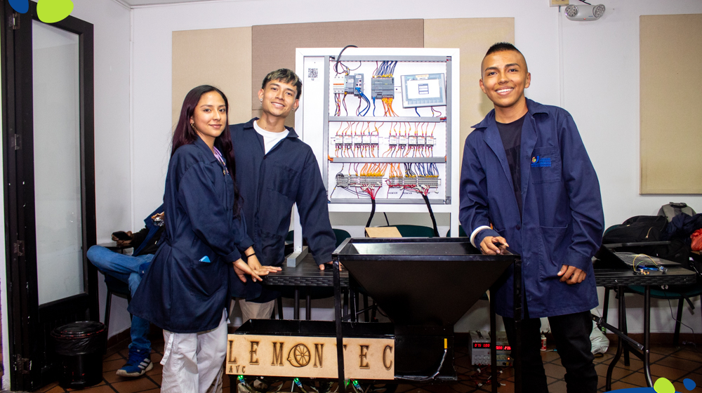 Dos chicos y una chica estudiante de Ingeniería Mecatrónica posando al lado de su proyecto titulado: Lemon Tec, en el Showroom Mechatronics.