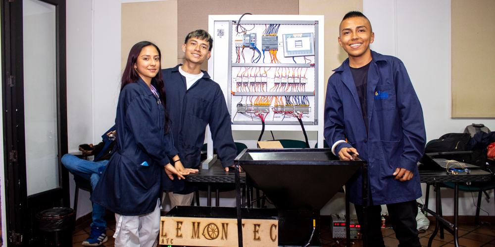 Dos chicos y una chica estudiante de Ingeniería Mecatrónica posando al lado de su proyecto titulado: Lemon Tec, en el Showroom Mechatronics.